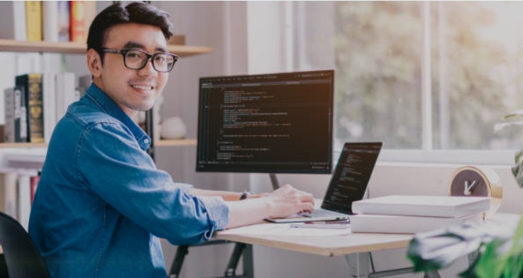 Hombre contento con una computadora al lado